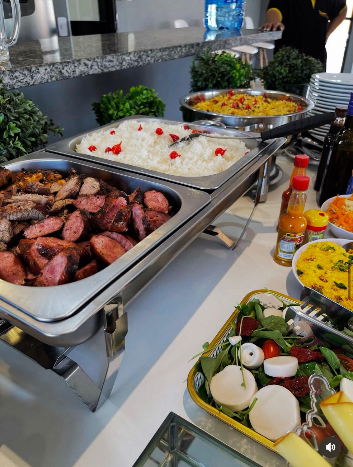 Mesa de buffet montada com churrasco, arroz e saladas